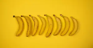Top view of tasty ripe bananas with blots on peel composed in row on yellow background